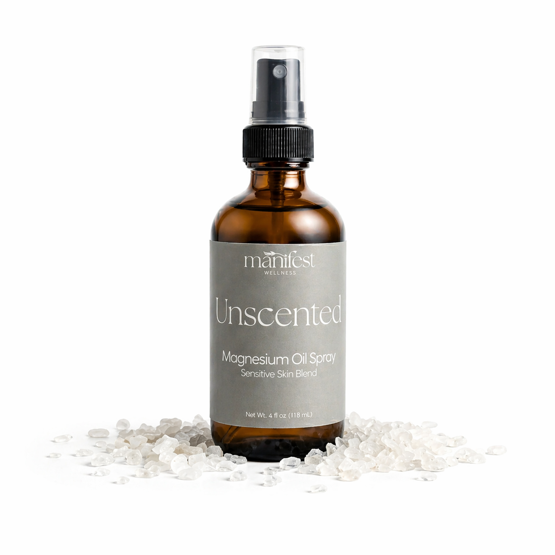 Brown spray bottle labeled Unscented Magnesium Spray by manifest wellness on a white background with magnesium chloride flakes.