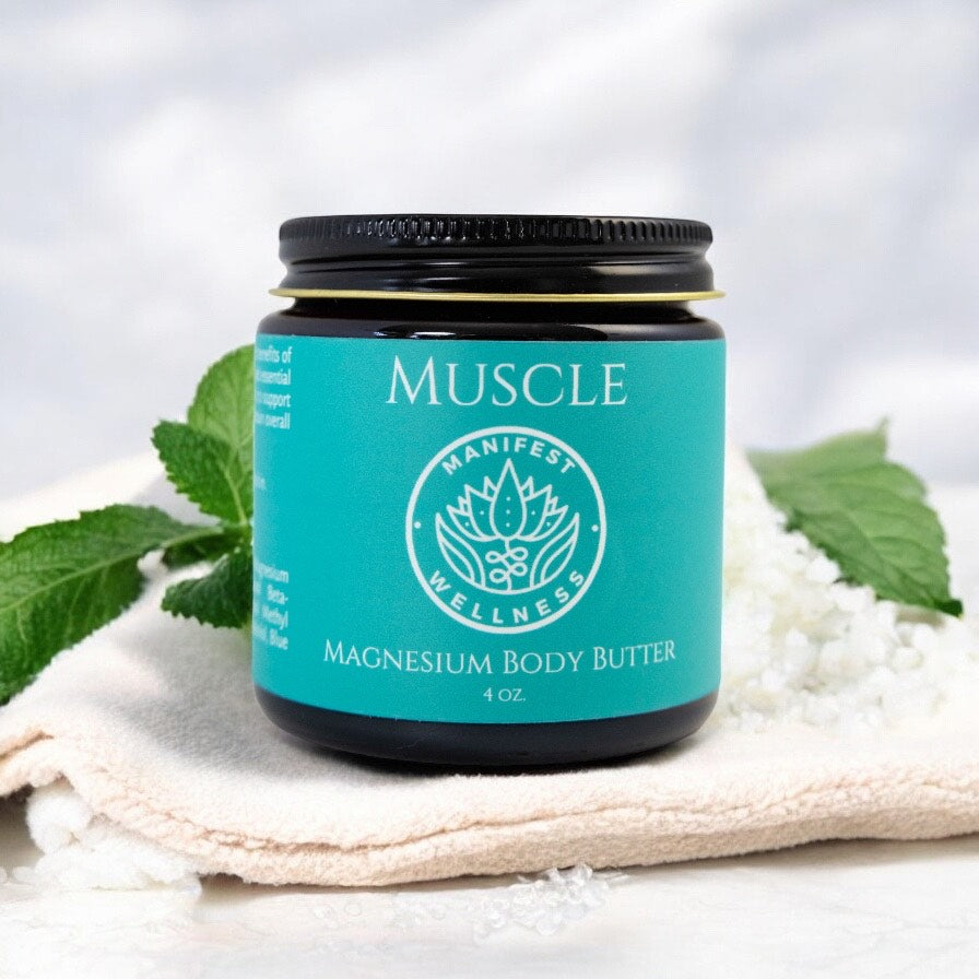 A glass jar of Muscle Magnesium Body Butter placed on a natural-colored loofah with mint leaves in the background.