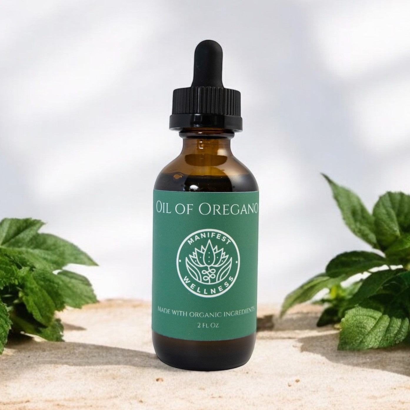 A glass bottle of Oil of Oregano from Manifest Wellness with green label and black dropper with a light background and oregano leaves around.